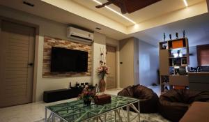 een woonkamer met een bank en een televisie aan de muur bij Palm Spring 301 in Patong Beach