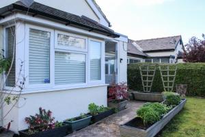 ein Haus mit Pflanzen nebeneinander in der Unterkunft Spacious 3-Bed Bungalow with Parking in Pensby by Rework Accommodation in Birkenhead