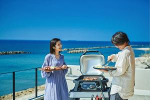Dos mujeres están cocinando comida en una parrilla en West Shore Plus, en Awaji