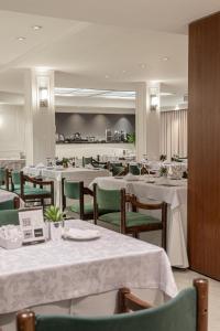 ブエノスアイレスにあるFeir's Park Hotel & Rooftopのダイニングルーム(白いテーブル、緑の椅子付)