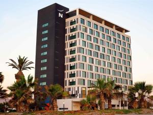 a tall building with palm trees in front of it at Novotel Arica in Arica