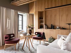 a living room with a couch and a table and chairs at Domaine de la Reine Margot Paris-Issy - MGallery Collection in Issy-les-Moulineaux