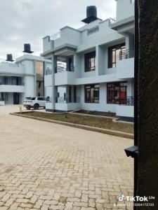 a large white building with a car parked in front of it at Moonshine walkers furnished apartments in Munyu