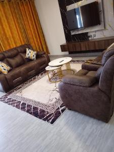 a living room with two couches and a table at Moonshine walkers furnished apartments in Munyu +2 photos