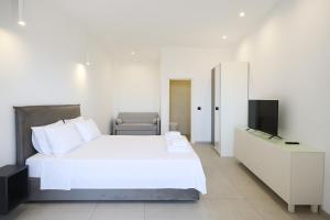 a bedroom with a white bed and a television at Mono Alex Afitos in Afitos
