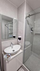 a white bathroom with a sink and a shower at Queen Emma's Place in Debrecen +7 photos