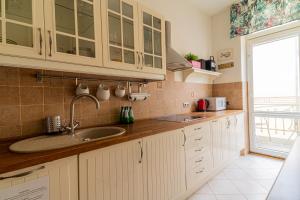a kitchen with white cabinets and a sink at Red Apartment Czyżewskiego by Grand Apartments in Sopot +6 photos