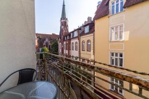 a balcony with a table and chairs on a city street at Red Apartment Czyżewskiego by Grand Apartments in Sopot