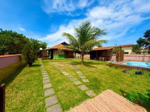 a garden with a palm tree and a swimming pool at Meu Refúgio Praia Seca in Araruama
