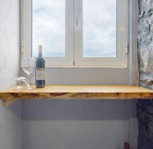 a bottle of wine and two glasses on a window sill at Casa dos avós in São Vicente +55 photos