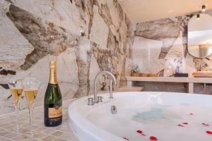 a bathroom with a tub and a bottle of champagne at Ecrin Romantique, Suite d'exception avec balnéo in Lyon