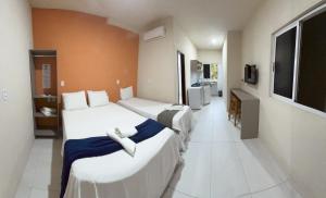 a hotel room with three beds and a tv at Bela Vista Japaratinga Flats e Temporada in Japaratinga