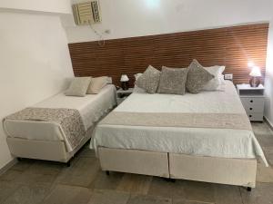 two beds in a hotel room with two beds at Pousada Pé na Areia Guarujá in Guarujá
