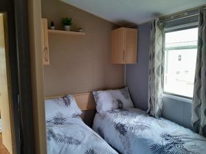 Dos camas en una habitación pequeña con ventana. en Static caravan - sleeps 8, en Great Driffield