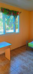 an empty room with two windows and a table at Guest House New Cal in Voh