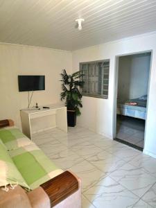 a living room with a bed and a tv at Casa Umuarama - Espaçosa e Confortável in Umuarama