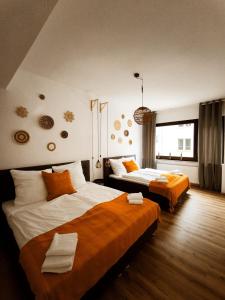 a hotel room with two beds with orange sheets at BioNaturSuite Kortum1745, HBF, Bermuda3Eck, Musikforum, Starlight Express, Museum in Bochum