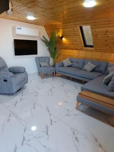 ein Wohnzimmer mit Sofas und einem Flachbildfernseher in der Unterkunft أكواخ المها oryx cottage in Adschlun