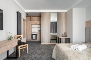 a bedroom with a bed and a desk and a kitchen at Rezydencja AMBRE in Łeba +144 photos