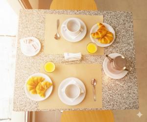 カンパーナにあるRM Campana Hotelの皿とコーヒーカップとクロワッサンが置かれたテーブル