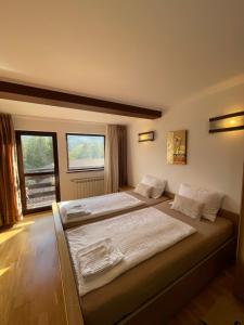 a bedroom with two beds and a large window at Vila Madisa in Buşteni
