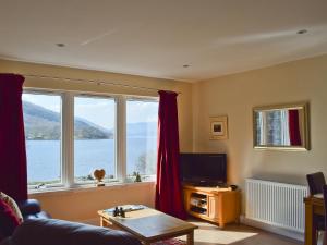 a living room with a large window with a view of the water at Lochearnside Lodge in Saint Fillans