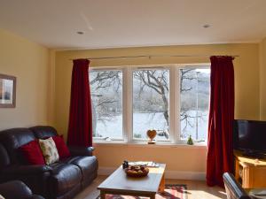 a living room with a couch and two large windows at Lochearnside Lodge in Saint Fillans