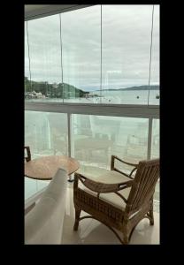 Una habitación con una mesa y sillas y una ventana grande. en Apto Frente Mar Itapema Canto da Praia, en Itapema