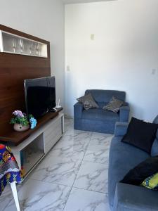 a living room with a blue couch and a tv at Casa com piscina e Ar condicionado in Camaçari