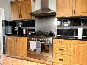 a kitchen with a stainless steel stove and wooden cabinets at Relax & Explore 3bed Home with Easy London Access in Harrow Weald