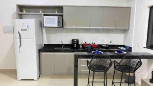 a kitchen with a white refrigerator and two chairs at 308-1 · Suíte Luxo Unievangélica/Ânima. 308 in Anápolis