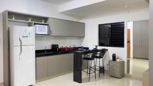 a kitchen with a refrigerator and a counter with stools at 308-1 · Suíte Luxo Unievangélica/Ânima. 308 in Anápolis