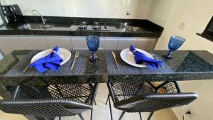 a kitchen with a table with two plates and blue glasses at 308-1 · Suíte Luxo Unievangélica/Ânima. 308 in Anápolis +17 photos