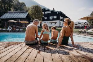a group of people sitting on a dock by a pool at Resl Resort in Flachau