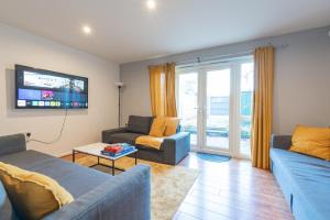 a living room with two couches and a tv at Cheerful 4-bedroom house with multiple car parking in Manchester
