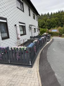 a fence with flowers on it next to a house at Ferienwohnung im Harz Wohlfühltempel nähe Lamspringe in Winzenburg