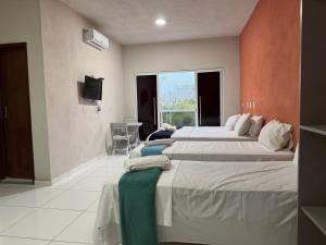a bedroom with two beds and a television in it at Bela Vista Japaratinga Flats e Temporada in Japaratinga +50 photos