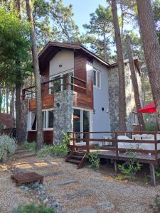 a house in the woods with a porch and benches at Amura in Mar Azul