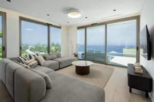 un soggiorno con divano, TV e ampie finestre di Villa Guindaste I Modern Villa with Sea View a Faial