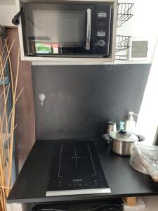 a microwave on top of a stove in a kitchen at Chambre-coin repas, sous terrasse, Proche gare in Franconville