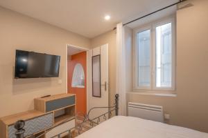 une chambre avec un lit et une télévision à écran plat dans l'établissement Bâtiment Les Iris, à Bourg-Saint-Andéol