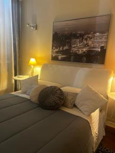 ein Schlafzimmer mit einem weißen Bett mit Kissen und einem Bild in der Unterkunft La Suite di Giulia in Ferrara