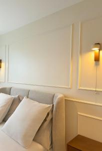 un lit avec des oreillers blancs et une lampe sur un mur dans l'établissement Villa Hortensia - Charming Cottage Near Fontainebleau, à Veneux-les-Sablons