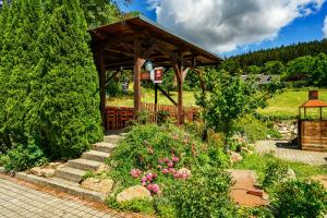 a garden with a wooden gazebo and some flowers at Penzion pod Ještědem in Světlá pod Ještědem