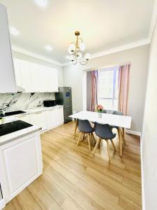 a white kitchen with a white table and chairs at Komfort City Residential Fam Luxe Complex with Mountain View in Zhezdi +2 photos