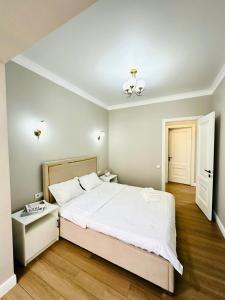 a bedroom with a large bed with white sheets at Komfort City Residential Fam Luxe Complex with Mountain View in Zhezdi
