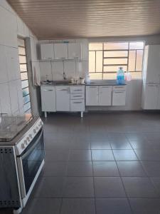 Una cocina con gabinetes blancos y un horno de estufa. en Casa Aconchegante, en Nova Odessa