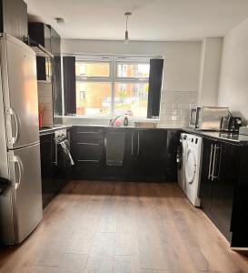 a kitchen with black and white appliances and a window at Sofi's Stay, Cosy 3 bed house, 5 mins Walk to Leeds City Centre in Leeds