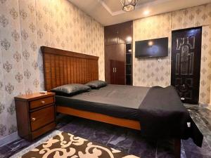 Un dormitorio con una cama y un televisor en la pared. en Hotel Gulberg Lodges MM Alam Road Gulberg ,Cavalry Lahore, en Lahore