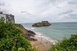 una playa con un edificio y el océano en Luxury Tenby Old Town Retreat just 1-minute to Beach with Parking, en Pembrokeshire